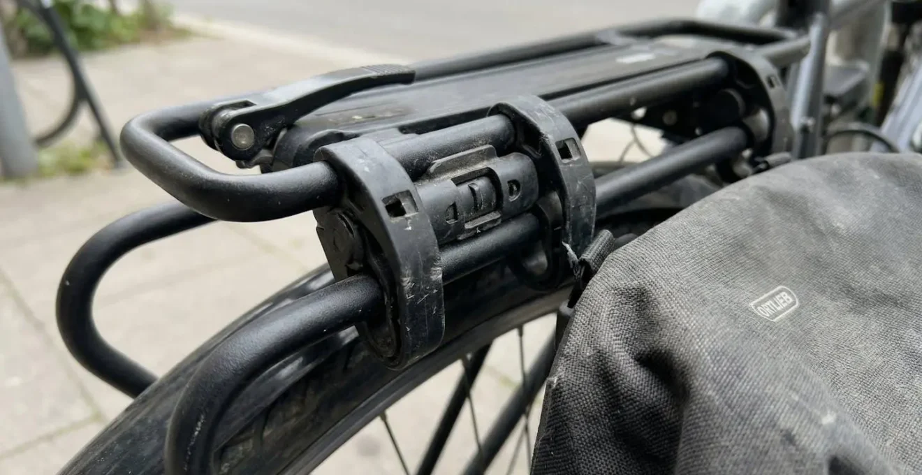 Gros plan sur une sacoche vélo fixée par clips sur un porte-bagages arrière, texture du tissu visible